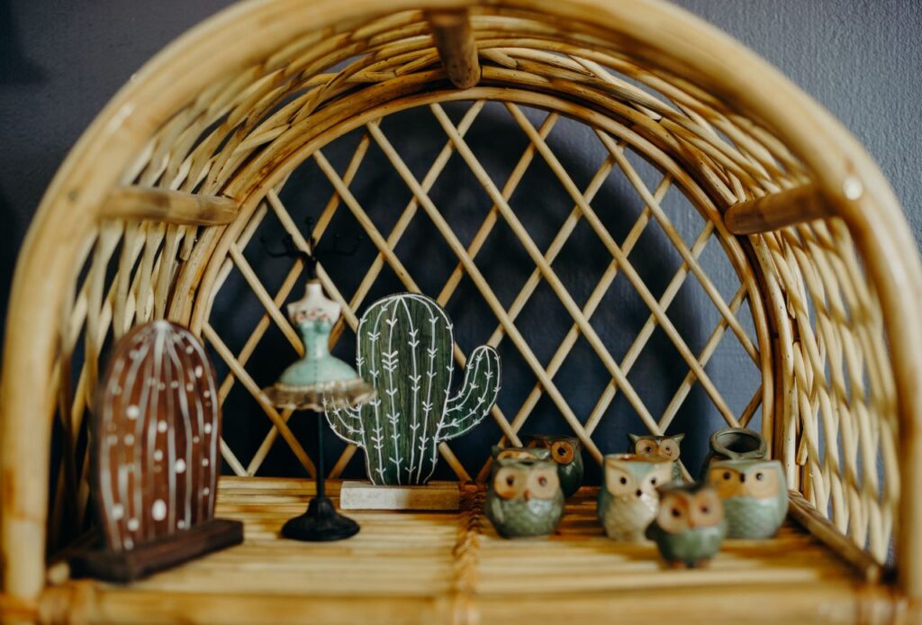Stylish shelf decor featuring owl figurines and cactus ornaments on a wicker shelf.